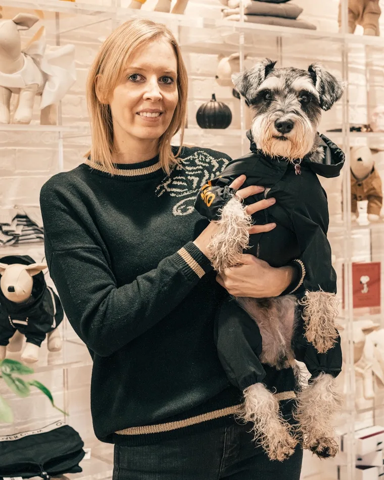 Tutora sorrindo com o cão no colo dentro da pet shop